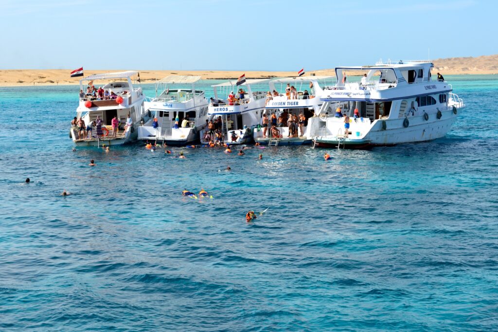 Snorkellers in clear water beside yachts off Hurghada